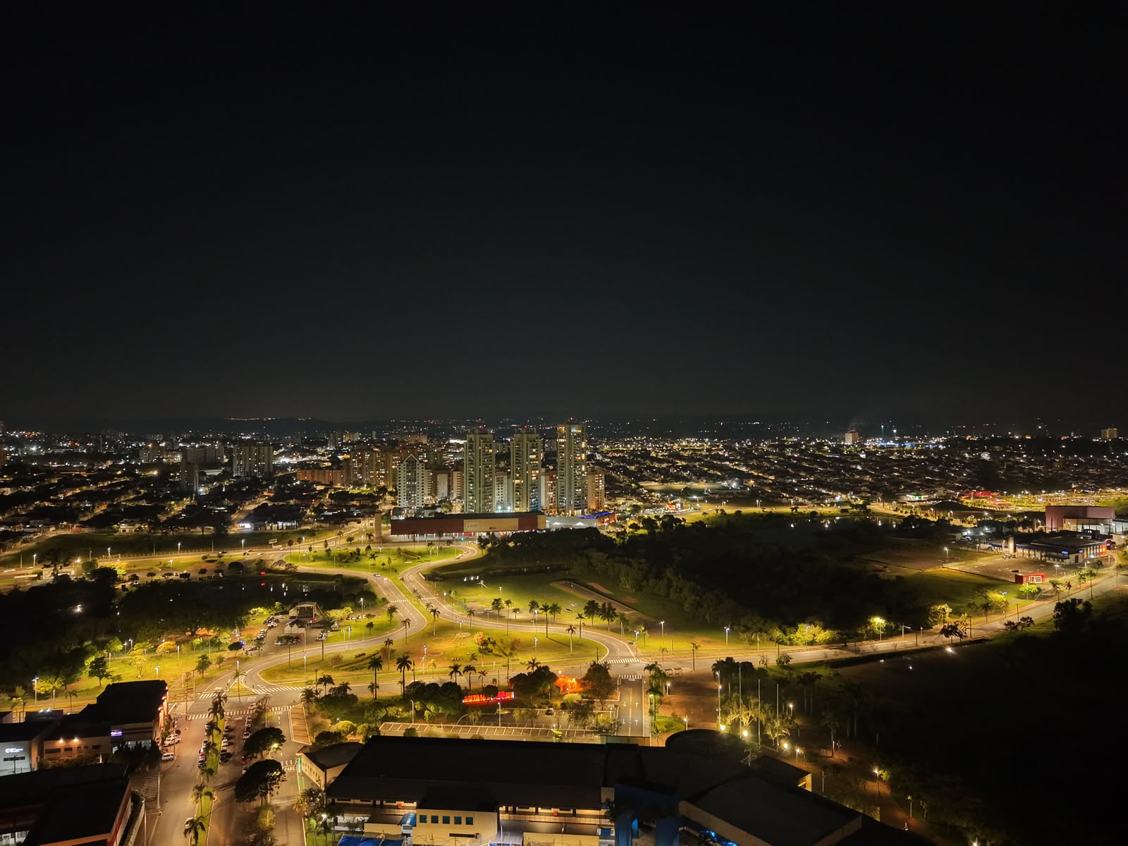 Avenida iluminada e torres da cidade à noite